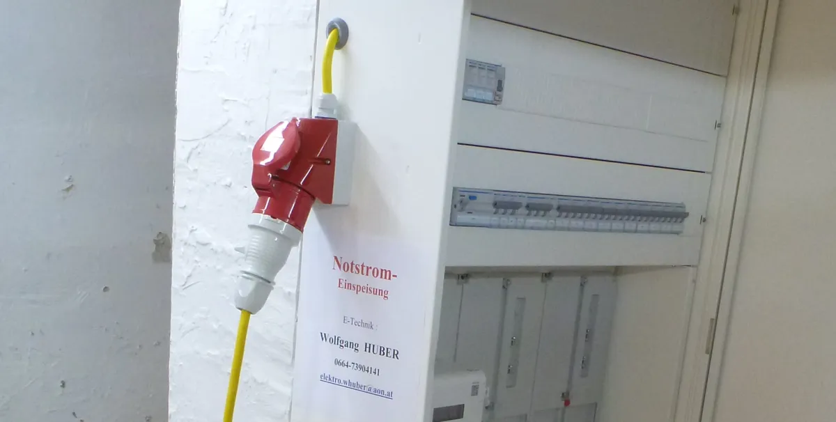 Roter fünfpoliger Einspeisestecker an der Wand neben dem Sicherungskasten